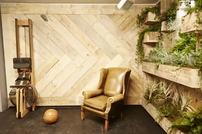 A leather wing-back chair in a quiet recovery corner against reclaimed timber and vertical planters