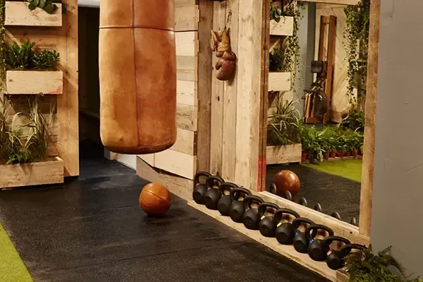 Bespoke private home gym studio with leather punch bag, hand-built wooden frame, kettlebells and vertical planters