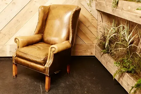 A leather wing-back chair in a quiet recovery corner against reclaimed timber and vertical planters