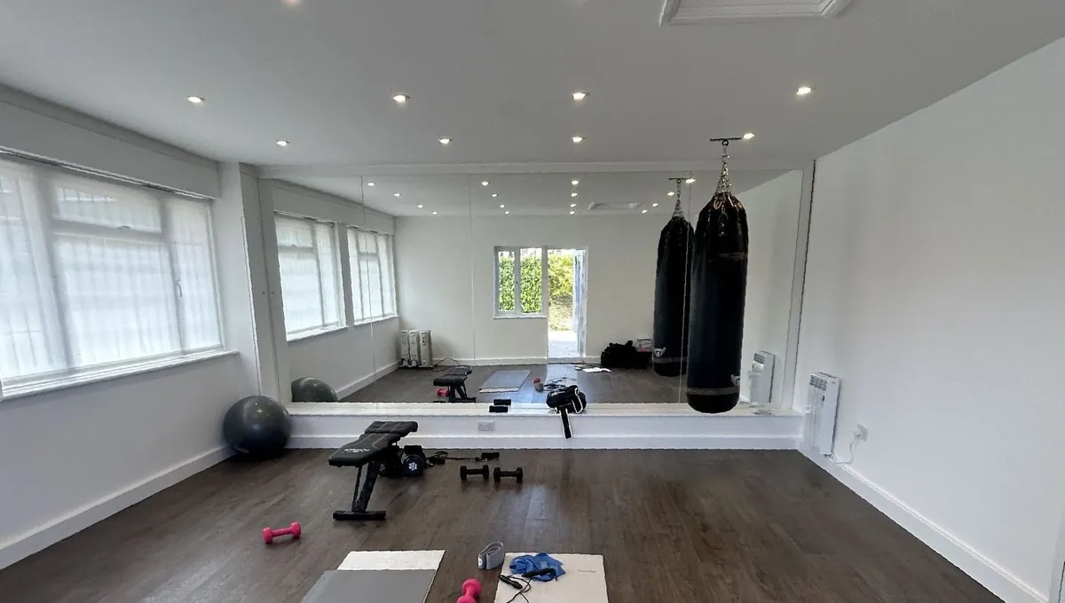 The same room before: white walls, mirrors, a hanging punch bag and basic equipment